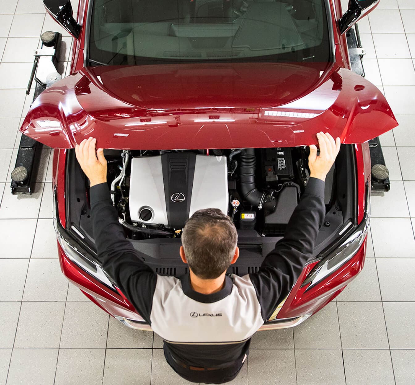 Lexus service technician popping the hood of a red Lexus