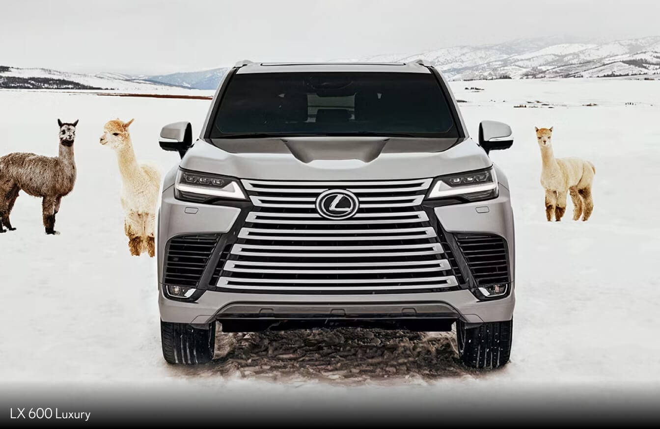 A front action shot of a white 2026 Lexus LX driving on a highway with a city skyline backdrop.