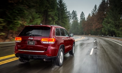 red Jeep Grand Cherokee Limited driving away from the camera in the rain