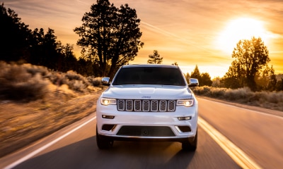 Jeep Grand Cherokee white Jeep Grand Cherokee driving towards camera with headlights on