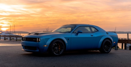 blue Dodge Challenger parked outside in front of a sunset