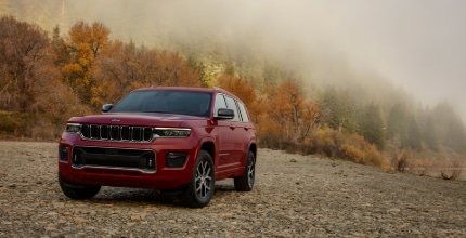 red Jeep Grand Cherokee L parked outside in front of a mountain