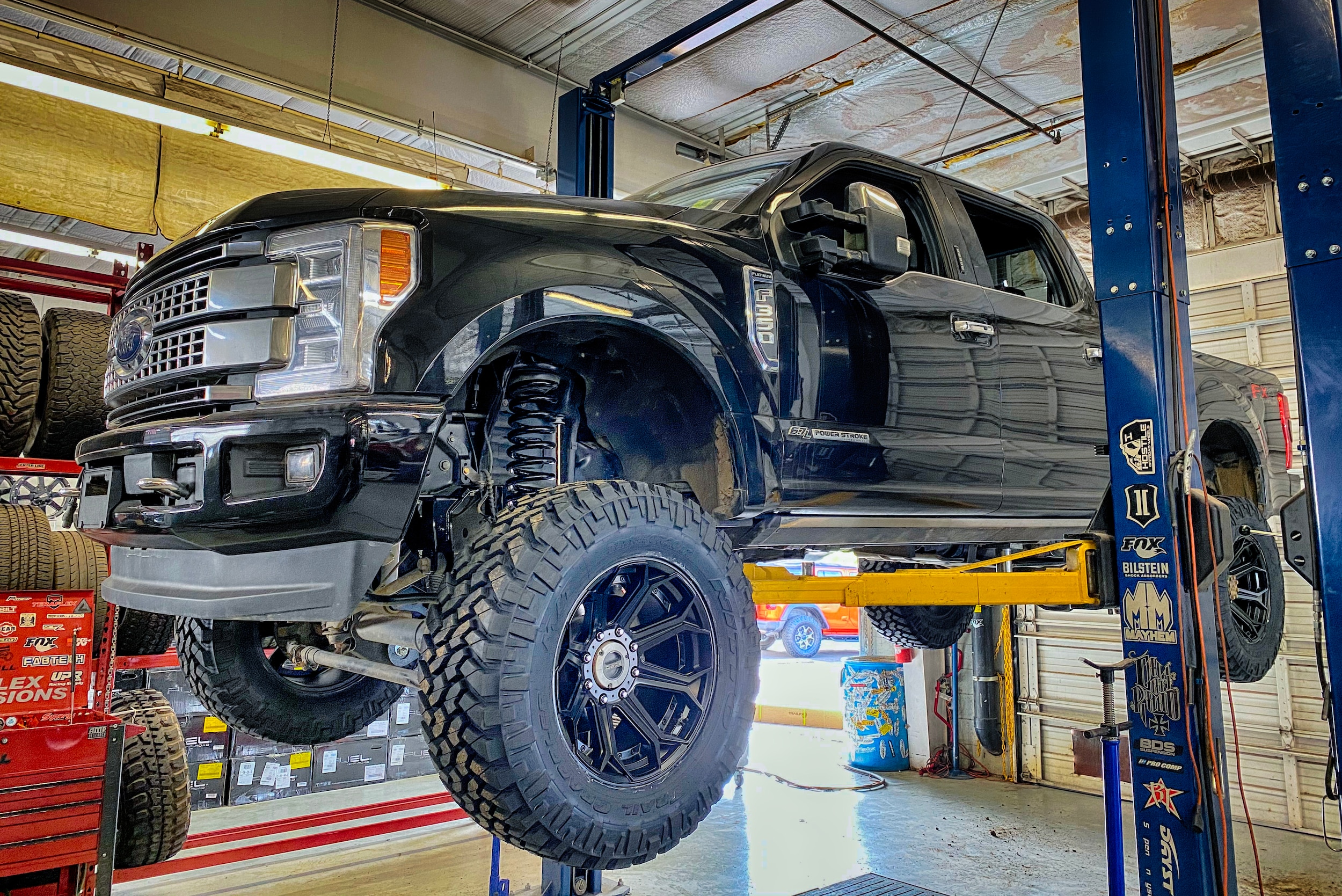 A customized Ford F-350 on a service lift at Lifted Trucks
