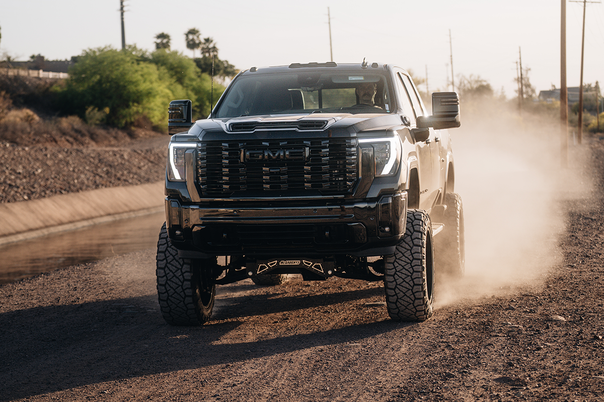  A lifted GMC Sierra 2500 Denali driving on a dirt road