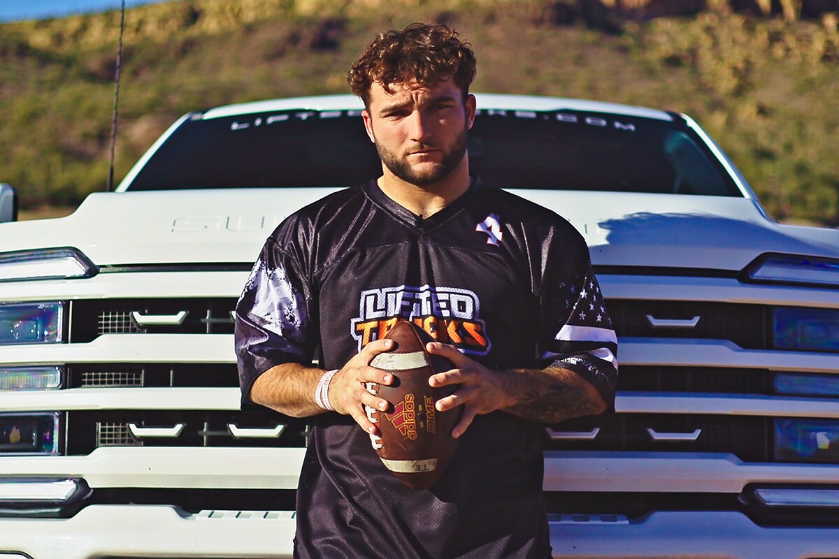  Cam Skattebo standing in front of a Ford Super Duty holding a football