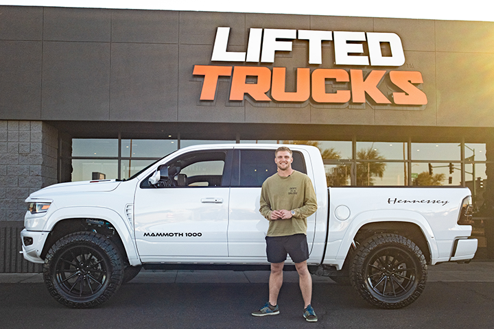  Trey McBride standing in front of a Mammoth 1000 Ram TRX Special Edition at a Lifted Trucks dealership