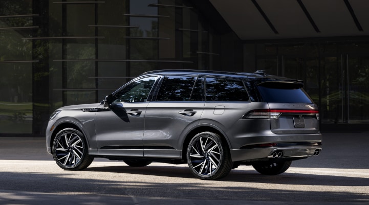 A gray 2025 Lincoln Black Label Aviator® SUV is parked outside a modern building.