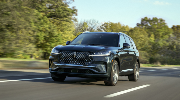 2026 Lincoln Aviator driving on a tree-lined road