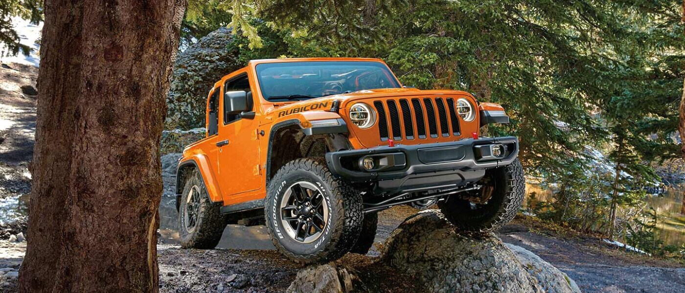 Orange Rubicon Driving over rock 