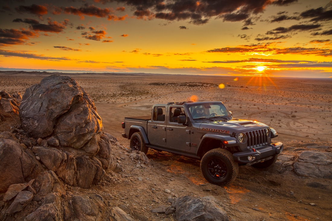 dark gray Jeep Gladiator truck bouldering through a desert pathway