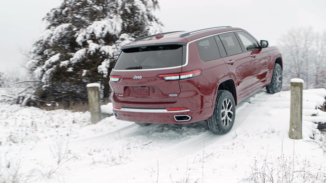 red Jeep Grand Cherokee L third-row SUV climbing up a snowy hill