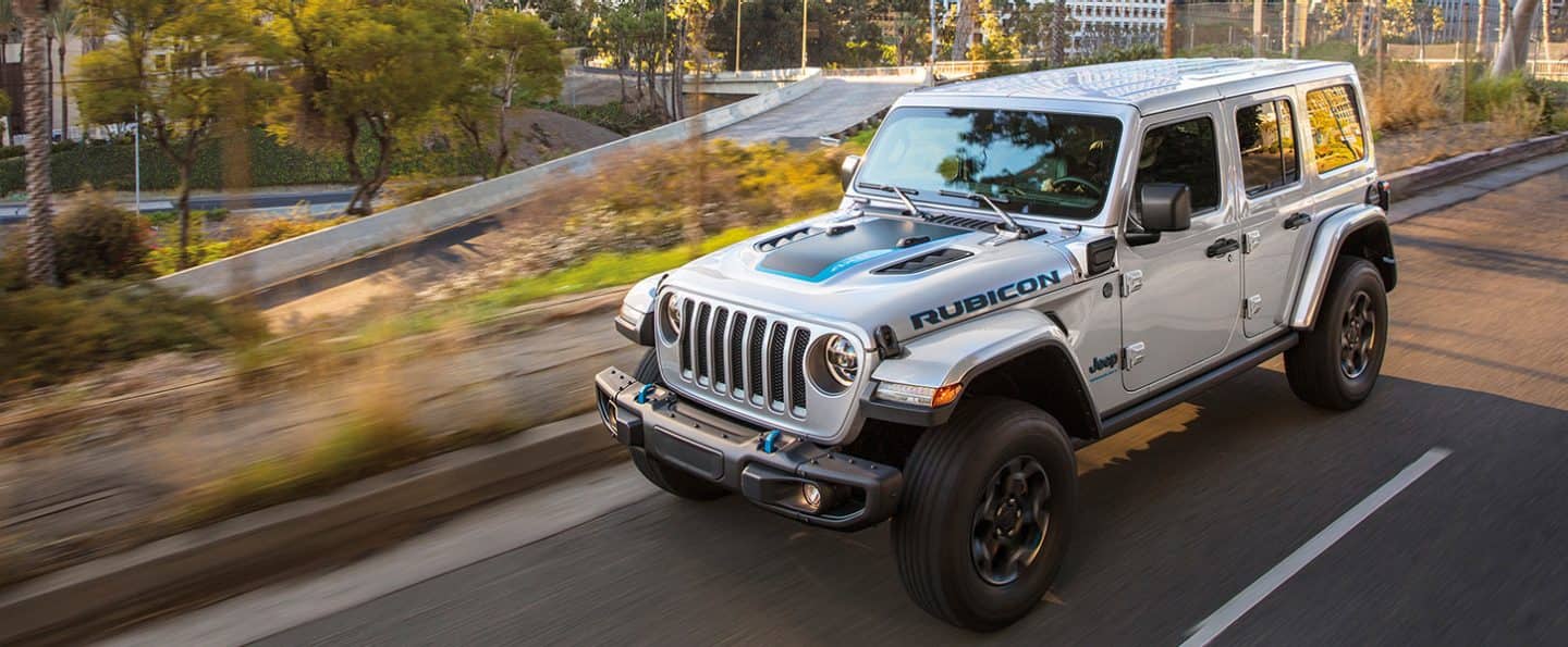 silver Jeep Wrangler 4xe hybrid SUV driving down the highway