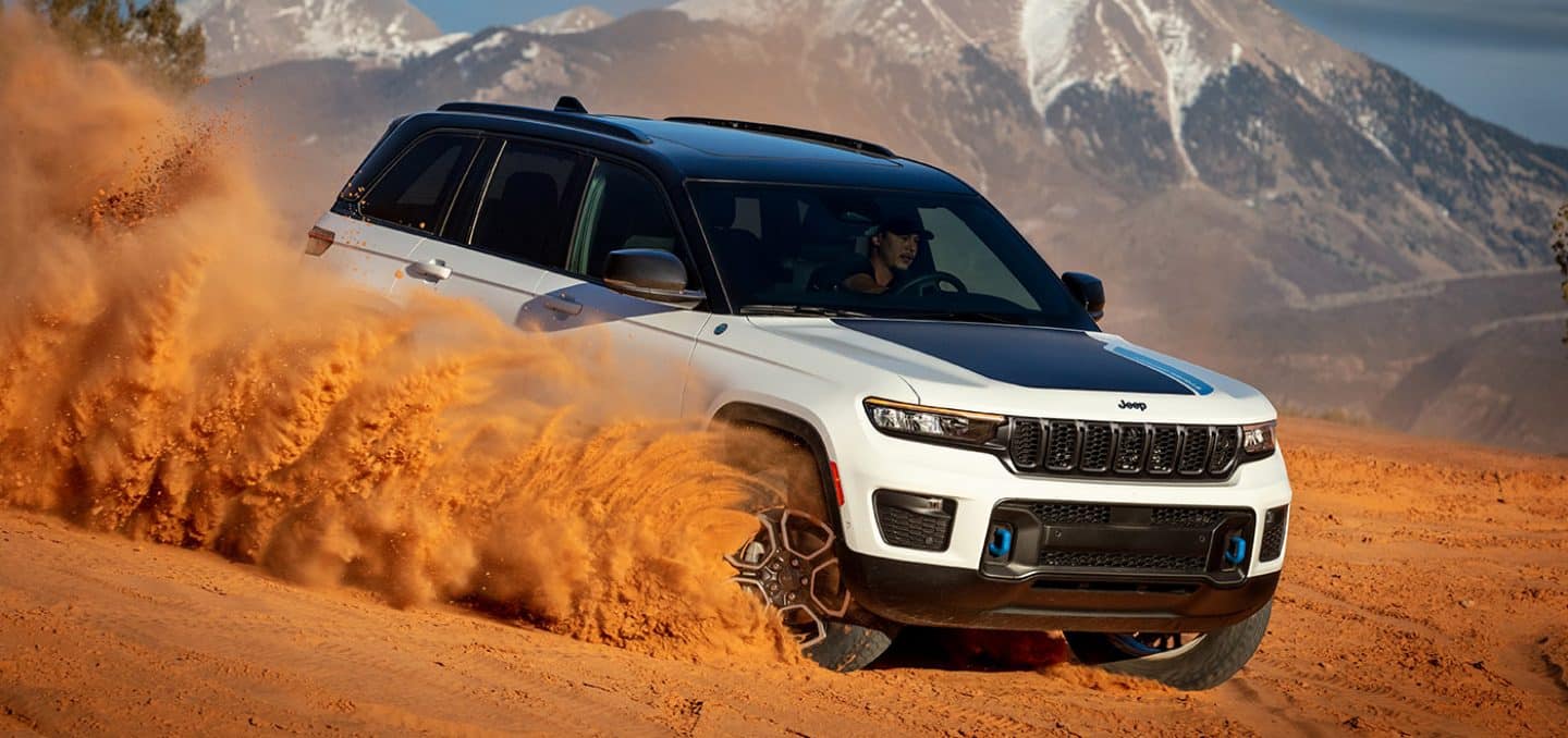 white Grand Cherokee 4xe SUV driving down through desert sand