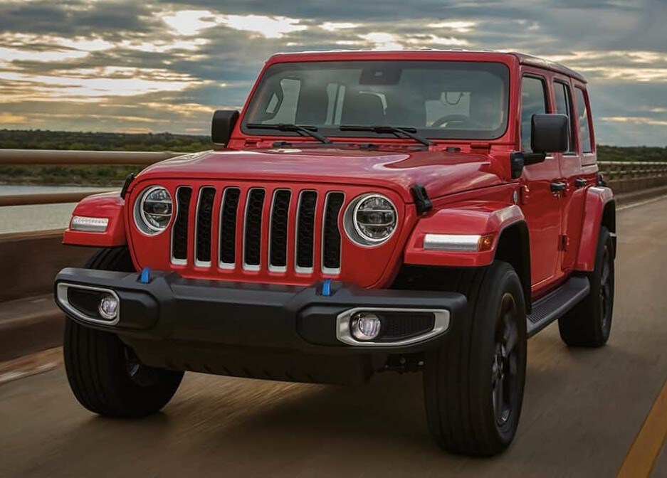 red Jeep Wrangler 4xe hybrid SUV driving down the highway