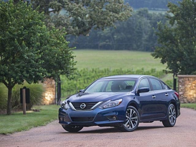 blue Nissan Altima sedan parked in front of a set of driveway gates