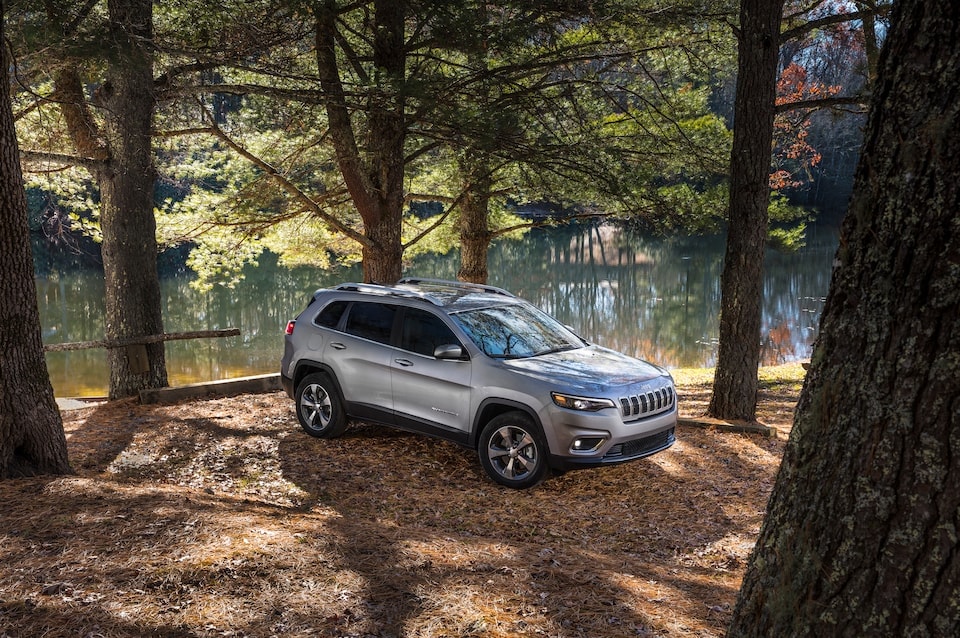 silver Jeep Cherokee SUV
parked in a tree-lined clearing by a river