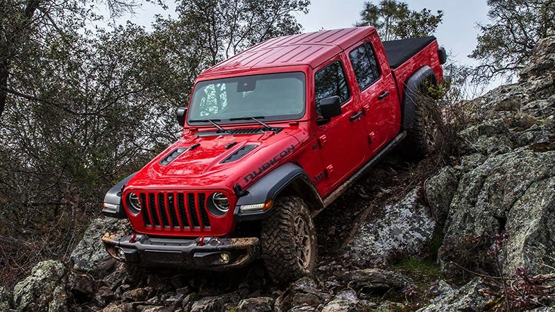 red Jeep Gladiator truck driving down a steep dirt hill