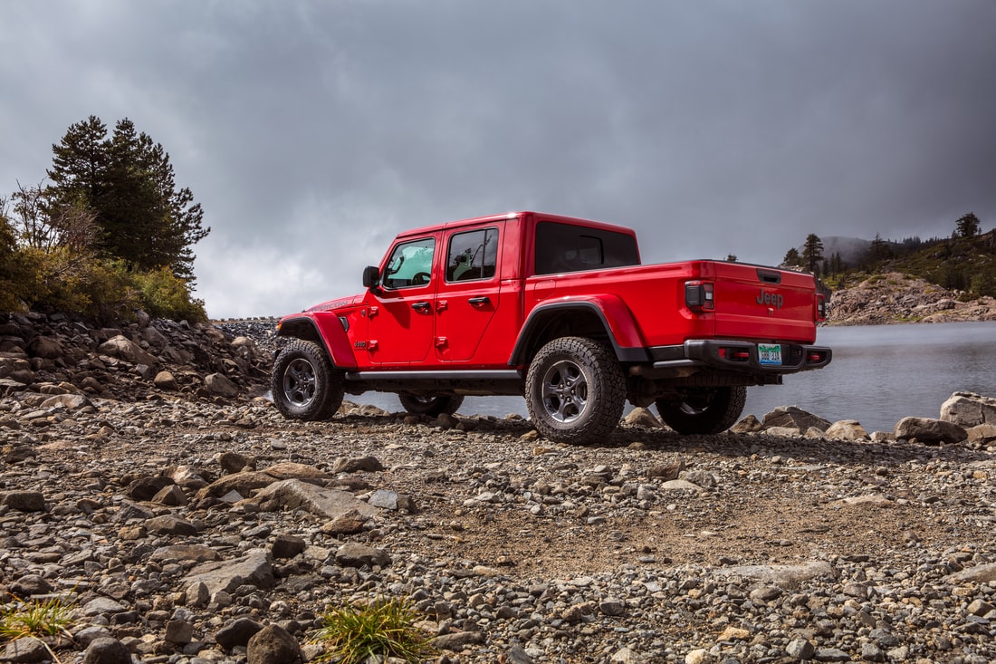 red Jeep Gladiator truck parked on the gravel next to a river, rear truck bed shown