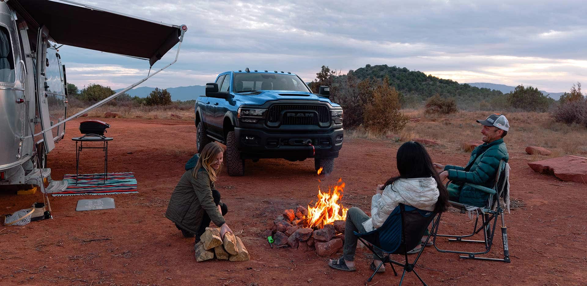 group of friends around a fire with a Ram 2500 heavy duty truck parked nearby