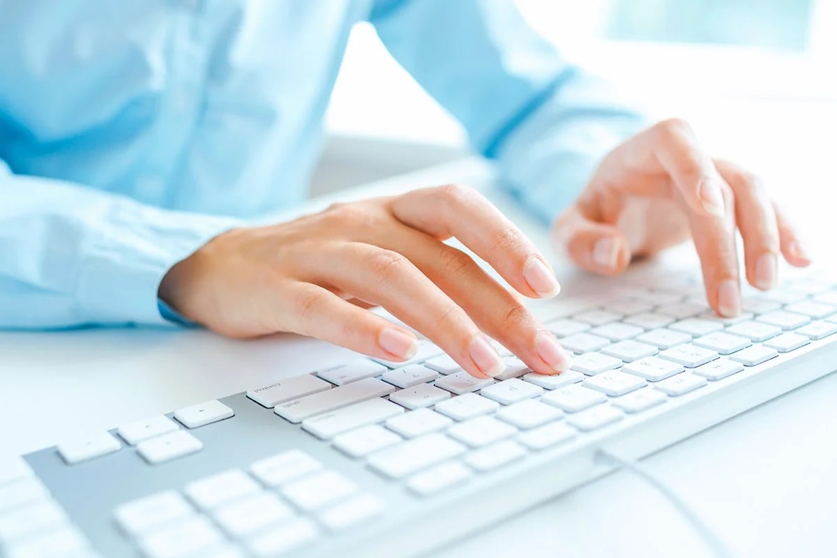 hands typing on a keyboard.