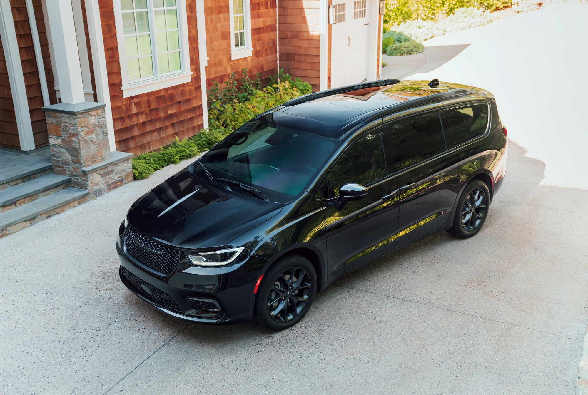 black Chrysler Pacifica minivan parked in front of a home