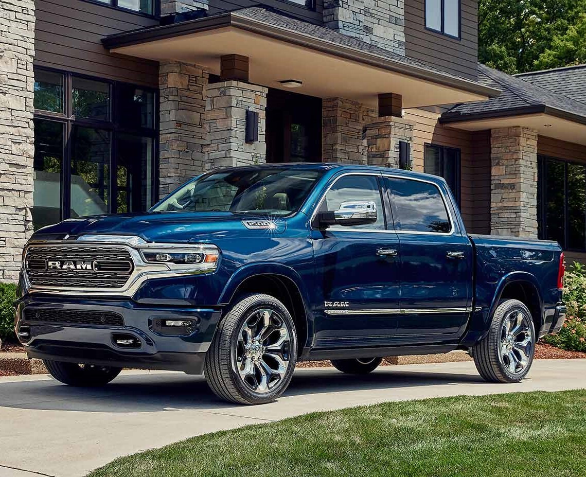 blue Ram 1500 truck parked in front of a large home with stone facing