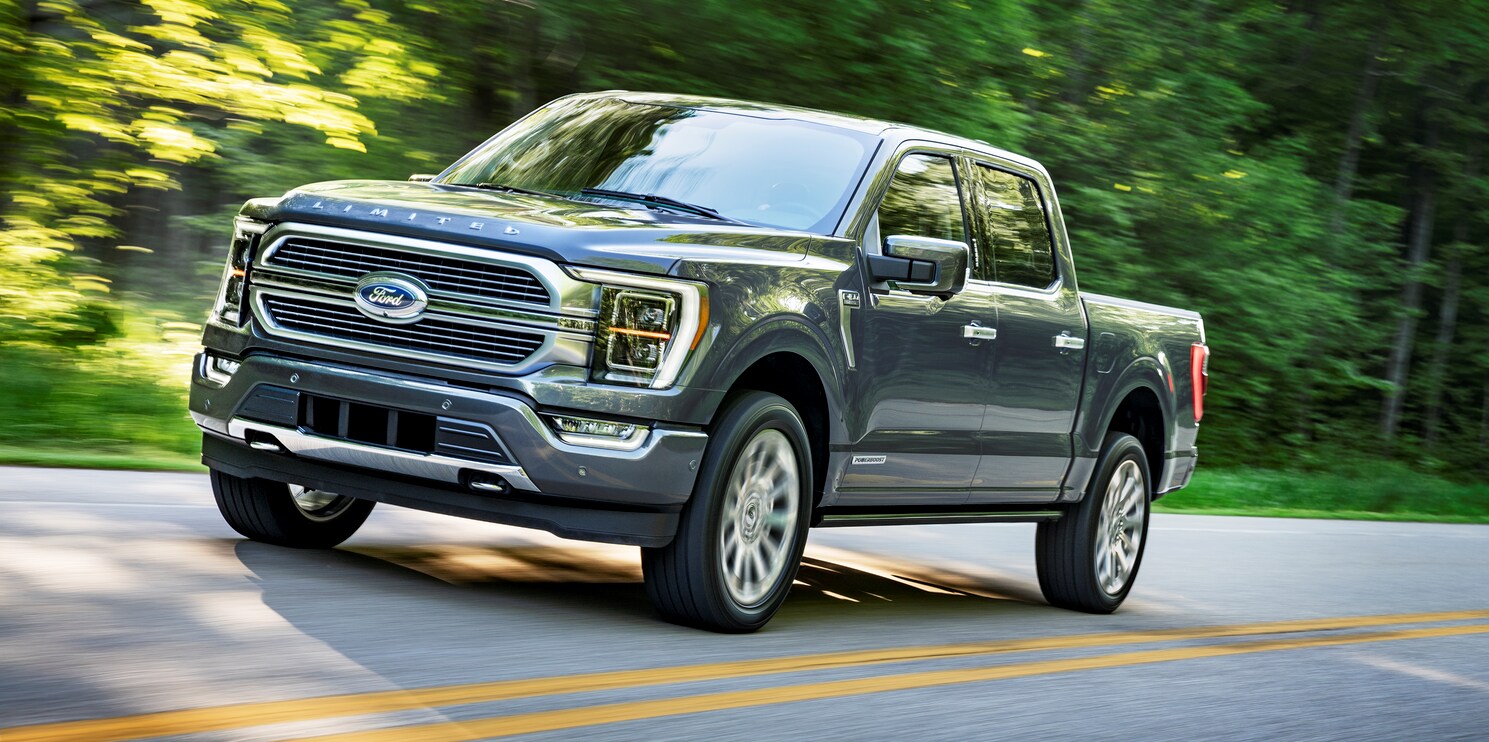 black Ford F-150 truck driving past a green blurred background