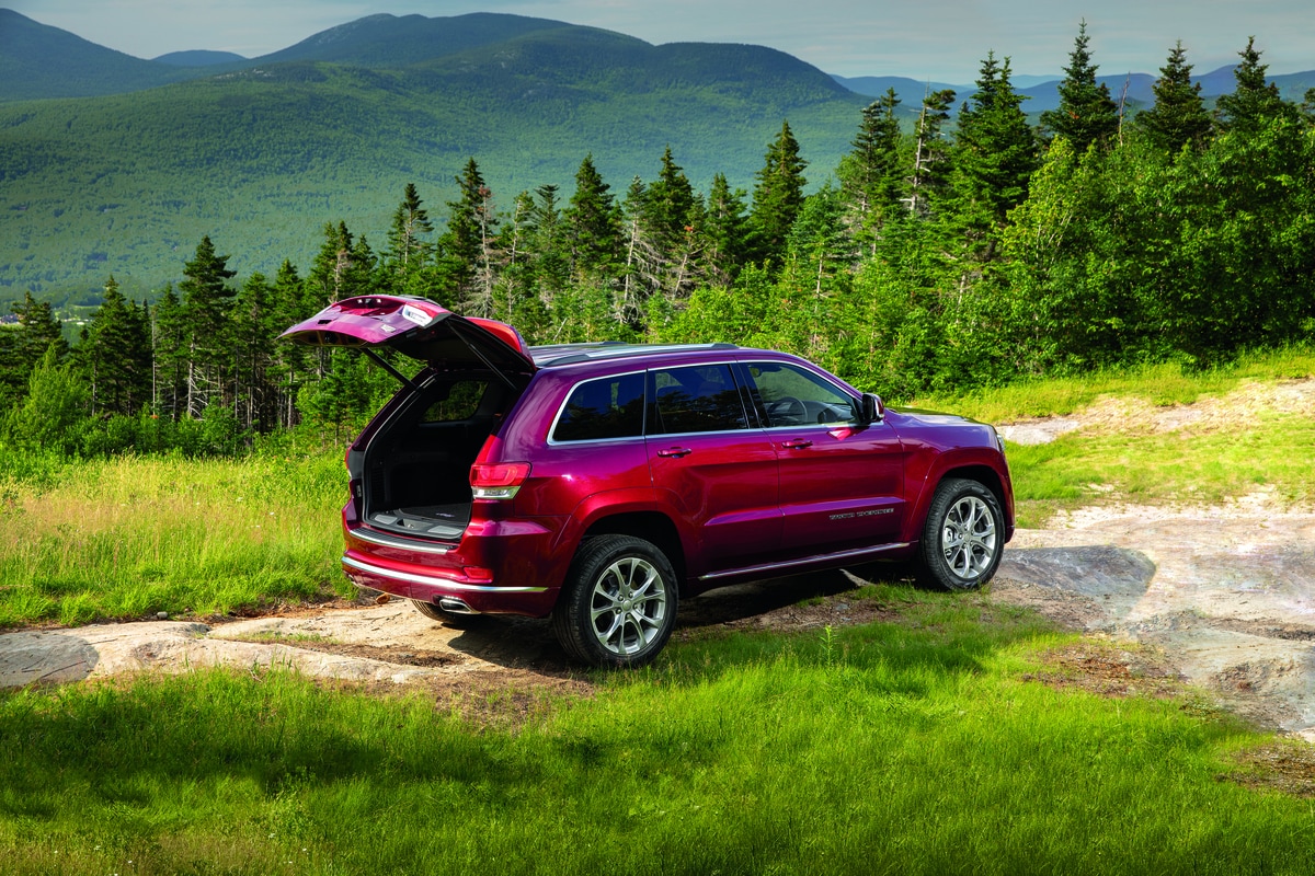 red Jeep Grand Cherokee SUV parked on a grassy hill with the trunk open