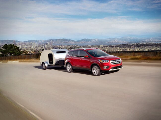 red Ford Escape SUV towing a silver teardrop trailer