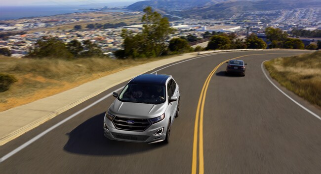 silver Ford Edge SUV driving down a highway