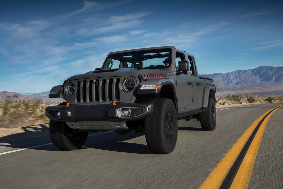 grey Jeep Gladiator truck driving down the highway, grill featured