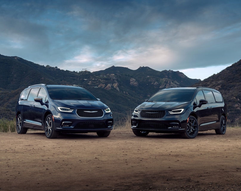 black and blue Chrysler Pacifica minivans parked next to a mountain range
