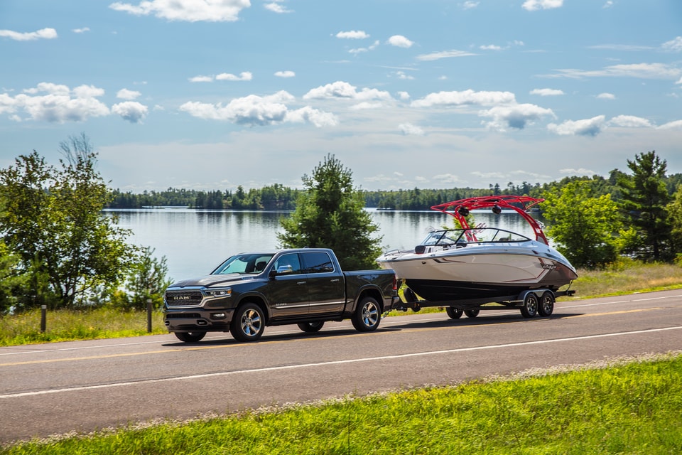 new Ram 1500 towing a boat near a lake