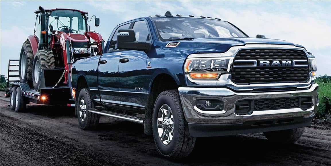 black Ram 2500 truck towing a small tractor