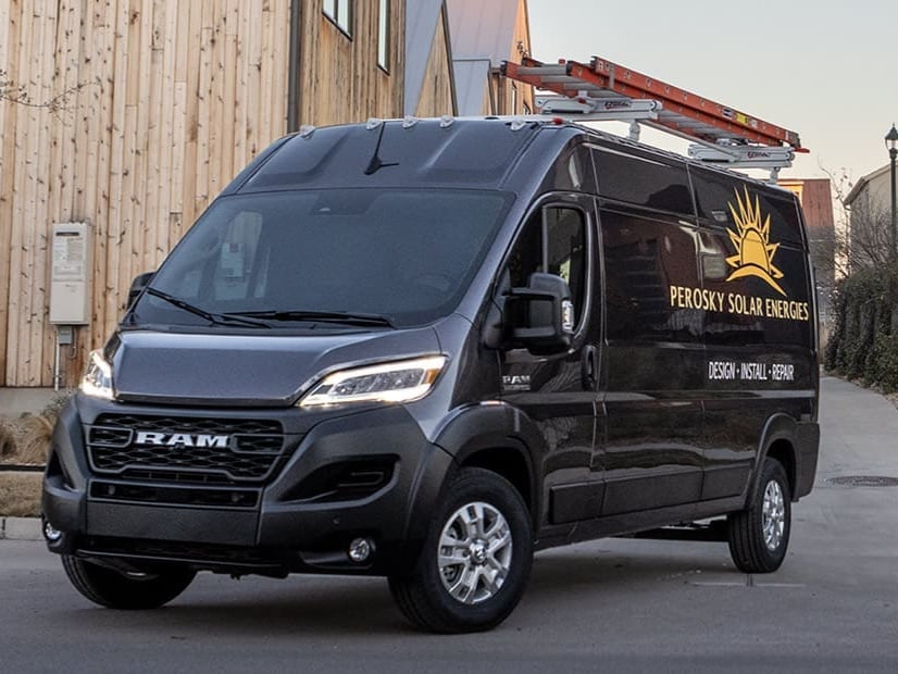black Ram 1500 ProMaster business van, parked with a ladder on top