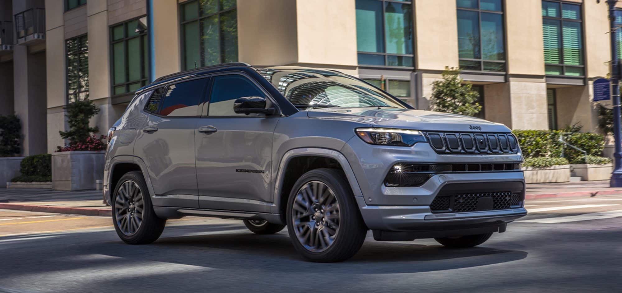 gray Jeep Compass SUV driving past a hotel or office building