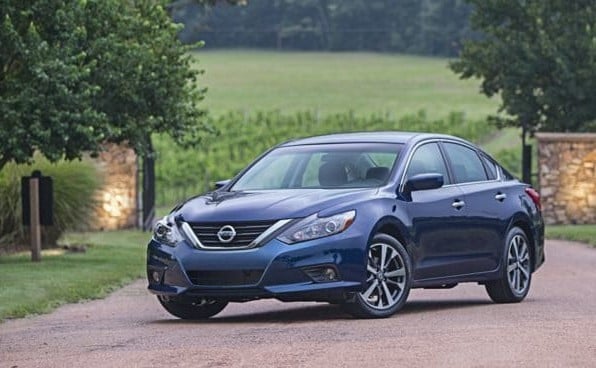 blue Nissan Altima parked in front of a gated driveway