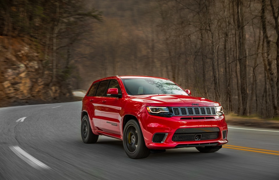 red Jeep Grand Cherokee driving through a wooded area