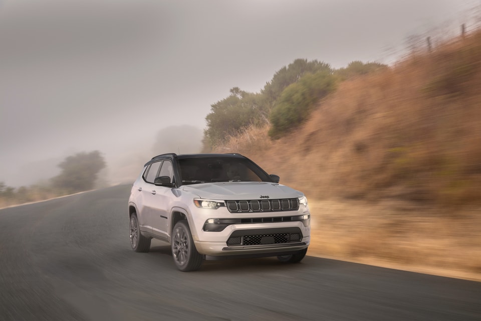 white Jeep Compass coming around a foggy hill