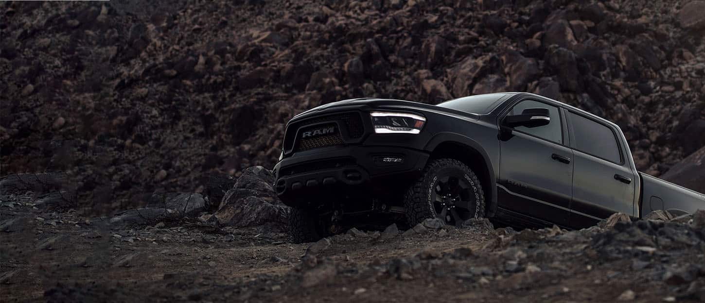 black lifted Ram truck bouldering over gravel
