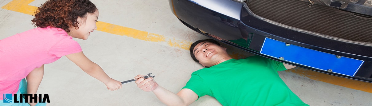Dad working on car, daughter helping