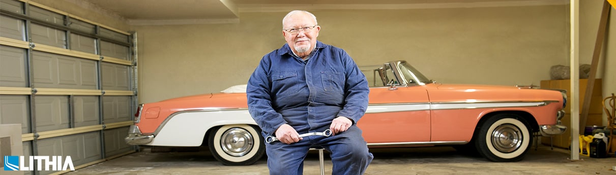 Older man in front of old car holding a wrench