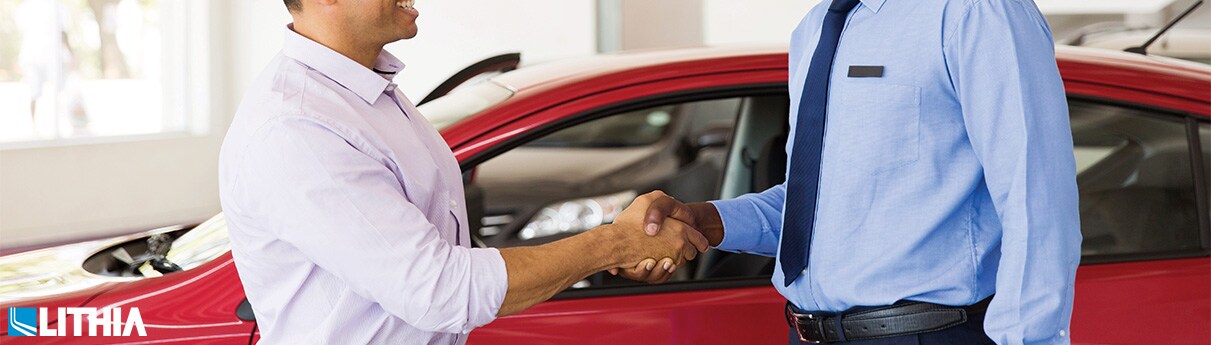 2 men shaking hands at a car dealership