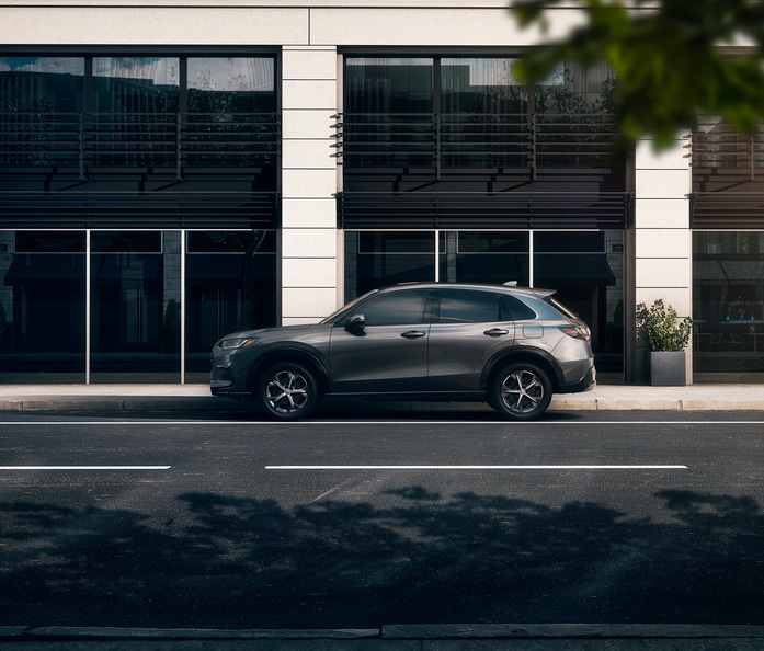 dark grey Honda HR-V SUV parked in front of a large windowed building