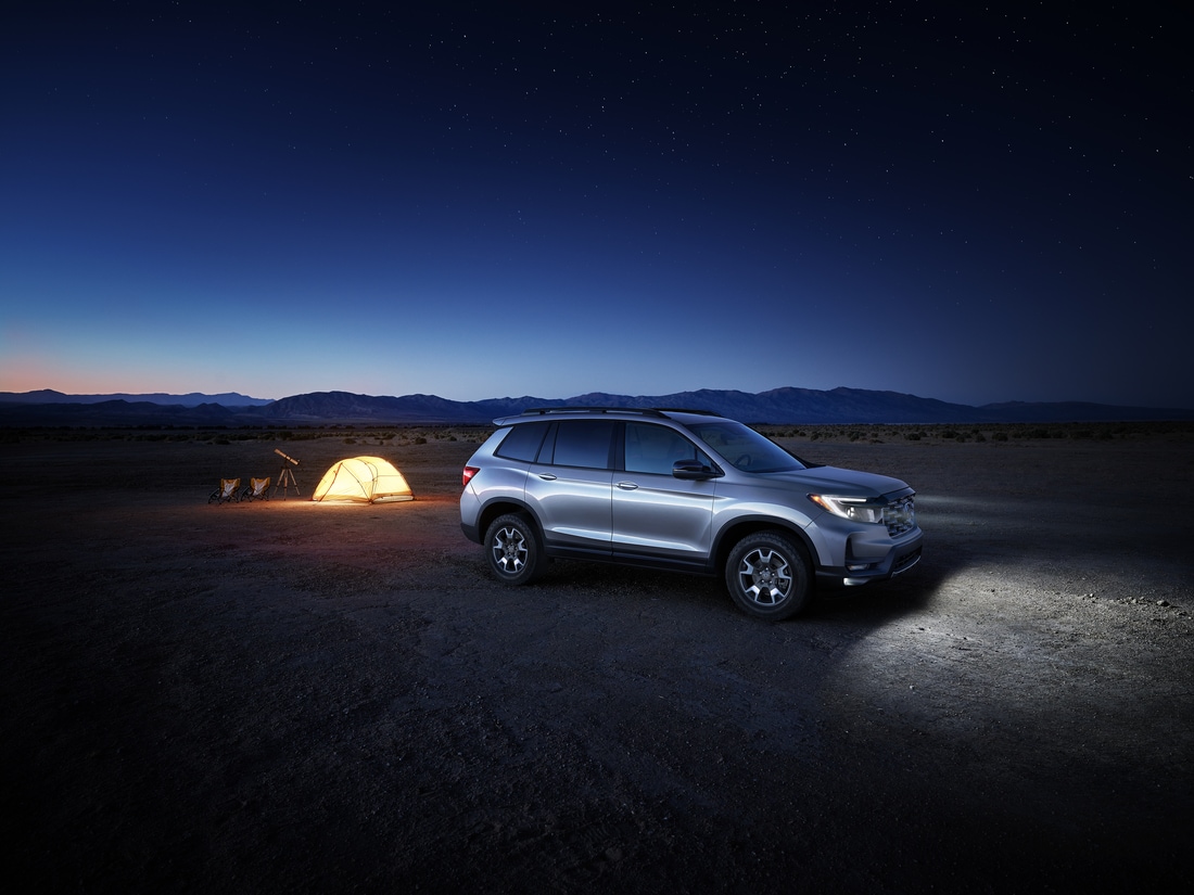 silver Honda Passport SUV parked in a desert next to a glowing campsite