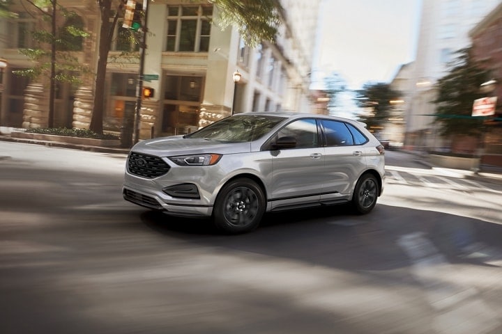 silver compact Ford SUV driving through a downtown city area