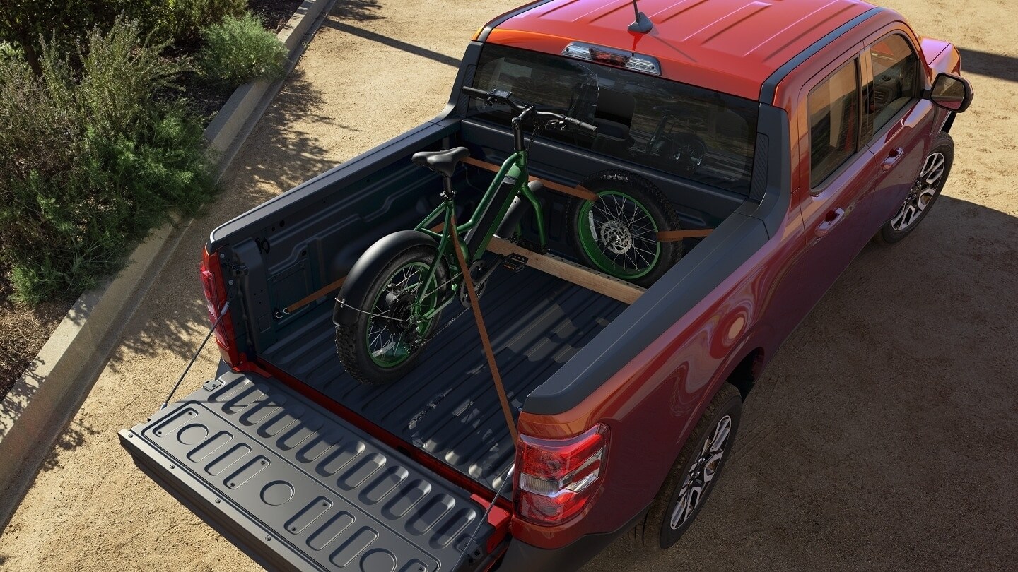aerial view of a red Ford Maverick hybrid truck parked with the bed opened