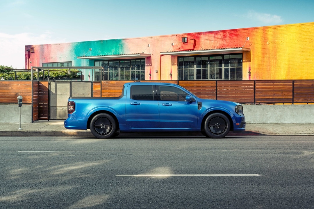 Ford Maverick parked next to a brick building with a musician bringing in equipment
