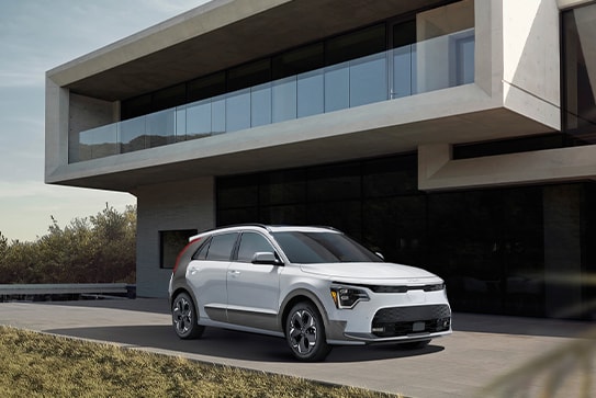 white Kia Niro EV parked near a very modern, boxy white home