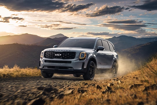grey Kia Telluride driving through a dusty, rocky area
